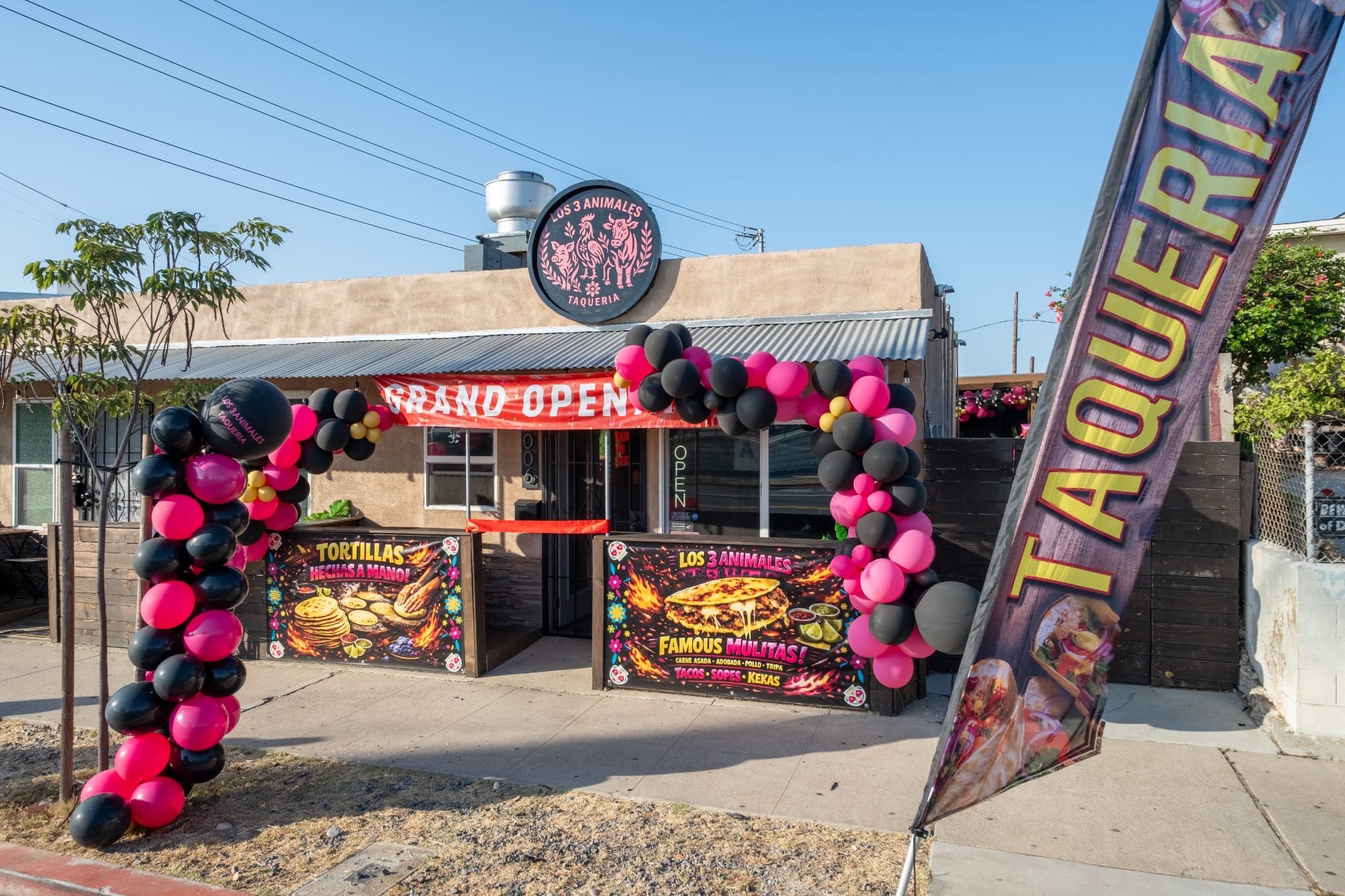 Front of the taquería with a "Taquería" feather flag on opening day
